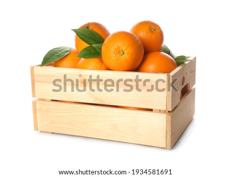 Fresh ripe oranges with green leaves in wooden crate on white background