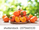 fresh ripe persimmon fruit on a wooden board on green background