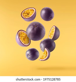 Fresh ripe raw passion fruit falling in the air isolated on yellow background. Zero gravity and food levitation concept. High resolution