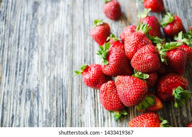 Fresh ripe strawberries on a wooden background. Organic juicy berries. Top view. Copy space for your text.