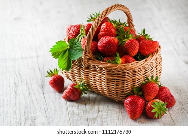 Fresh ripe strawberries in wicker basket on white rustic table. 