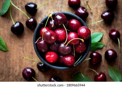 Fresh Ripe Sweet Cherries In A Bowl With Droplets Of Water. Overhead View On Dark Rustic Wooden Background, Closeup