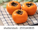 Fresh ripe sweet persimmon kaki fruit on wooden table background.