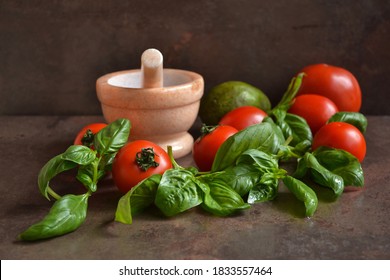 Fresh Ripe Tomatoes, Basil And Avocado With Granite Pestle And Mortar. Kitchen Background. 