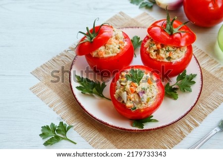 Fresh ripe tomatoes stuffed with canned tuna and vegetables salad on plate with white wood background.Easy and healthy Italian summer salad.Top view.Copy space