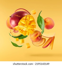 Fresh ripe whole and sliced mango and peaches with green leaves falling in the air isolated on yellow background. Zero gravity, food levitation conception. High resolution image. - Shutterstock ID 2195143149