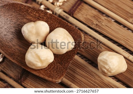 Fresh roasted macadamia nuts on wooden surface. Healthy snack with delicious nutty flavor and natural shell texture displayed on rustic wood.