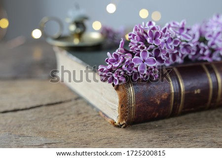 Fresh romantic, lilac  flowers on  antique book with candlestick  on old wooden background, soft focus.  Vintage, rustic, grunge, style. Celebration, Mothers day, memory card, appreciation symbol.