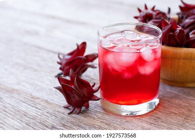 Fresh Roselle flower ( Jamaica sorrel, Rozelle or hibiscus sabdariffa ) and glass of sorrel juice ice tea isolated on wooden table background. 