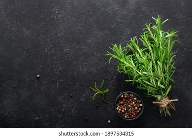 Fresh rosemary and a mix of peppers against a black concrete background.