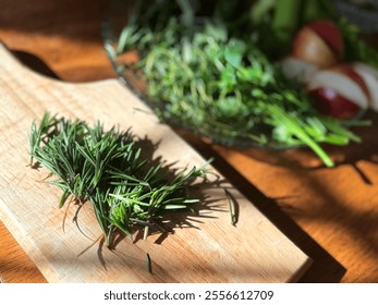 Fresh rosemary sprigs placed on a wooden cutting board, ready to be chopped or used in cooking preparations. A plate of other ingredients sits behind on a plate. The scene is covered in warm sunlight. - Powered by Shutterstock