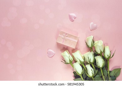 Fresh roses flowers with gift box and hearts on a pink background. Place for text. Post card, greeting card mock up.