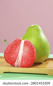Fresh ruby red grapefruit cut in half displaying vibrant pink flesh on wooden cutting board against colorful background for healthy eating concept