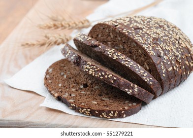 fresh rustic wholemeal rye bread, sliced on a wooden board, closeup.