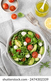 Fresh salad with arugula, mozzarella, tomatoes and avocado in a bowl. Healthy vegetarian dish