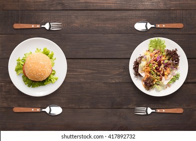 Fresh salad and burger on the wooden background. contrasting food.