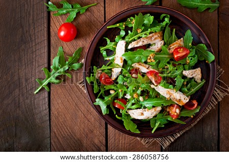 Fresh salad with chicken breast, arugula and tomato. Top view