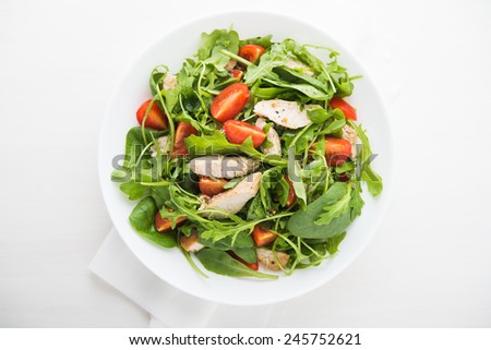 Fresh salad with chicken, tomato and greens (spinach, arugula) top view. Healthy food.