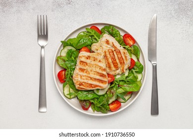 Fresh Salad - Cucumbers, Tomato, Arugula, Chards Leaves And Chicken Fillet Grill In A Plate On The Table. Top View. Healthy Diet Food.