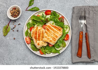 Fresh Salad - Cucumbers, Tomato, Arugula, Chards Leaves And Chicken Fillet Grill In A Plate On The Table. Top View. Healthy Diet Food.