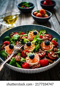 Fresh Salad - Goat Cheese, Raspberries, Blueberries, Pecan Nuts, Cherry Tomatoes, Pickled Radishes And Leafy Greens On Wooden Table 