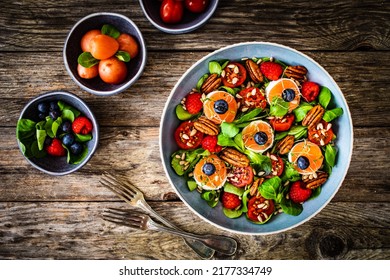 Fresh Salad - Goat Cheese, Raspberries, Blueberries, Pecan Nuts, Cherry Tomatoes, Pickled Radishes And Leafy Greens On Wooden Table 