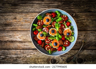 Fresh Salad - Goat Cheese, Raspberries, Blueberries, Pecan Nuts, Cherry Tomatoes, Pickled Radishes And Leafy Greens On Wooden Table 