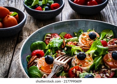 Fresh Salad - Goat Cheese, Raspberries, Blueberries, Pecan Nuts, Cherry Tomatoes, Pickled Radishes And Leafy Greens On Wooden Table 