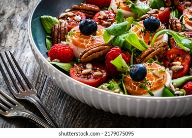 Fresh Salad - Goat Cheese, Raspberries, Blueberries, Pecan Nuts, Cherry Tomatoes, Pickled Radishes And Leafy Greens On Wooden Table 