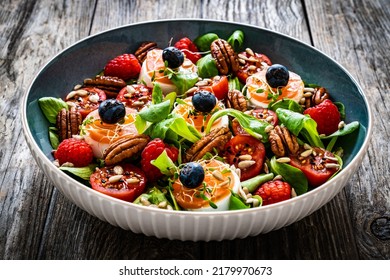 Fresh Salad - Goat Cheese, Raspberries, Blueberries, Pecan Nuts, Cherry Tomatoes, Pickled Radishes And Leafy Greens On Wooden Table 