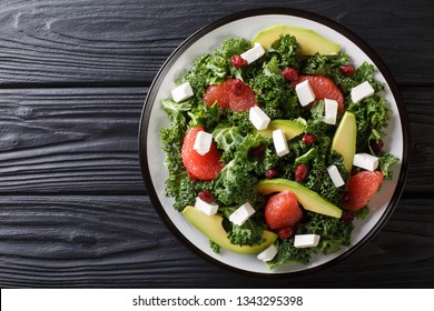 Fresh Salad Of Kale, Avocado, Grapefruit, Cheese And Dried Cranberries Close-up On A Plate On The Table. Horizontal Top View From Above
