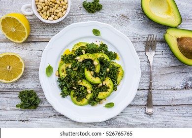 Fresh salad with kale leaves and avocado on a white plate on wooden table. - Powered by Shutterstock