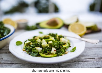 Fresh salad with kale leaves and avocado with pear on a white plate on wooden table. - Powered by Shutterstock