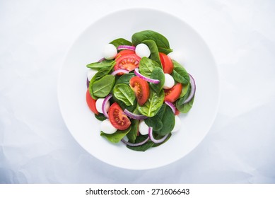 Fresh Salad With Mozzarella Cheese, Tomato, Spinach And Purple Onion On White Background Top View. Healthy Food.