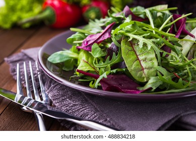 Fresh Salad Plate With Mixed Greens (arugula, Mesclun, Mache) On Dark Wooden Background Close Up. Healthy Food. Green Meal.