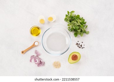 Fresh salad. Preparation of the recipe. Raw ingredients. Trendy and fresh food. Healthy nutrition. Salad leaves, avocado, boiled eggs, onion, oil. Top view, white background. Minimalist. Concept. - Shutterstock ID 2211538557