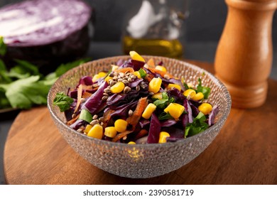  Fresh salad with red cabbage, carrots, hemp seeds and corn in a bowl on the table. High quality photo