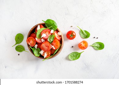 Fresh salad with tomatoes, cottage cheese and spinach in wooden bowl on white background. Top view. - Powered by Shutterstock