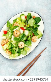Fresh salad with vegetables and seafood, shrimps in a white plate. Prawns salad. Top view. - Shutterstock ID 2393945767