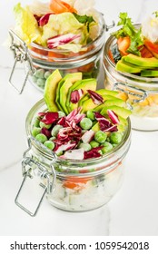 Fresh salads in jar with fresh vegetables and healthy dressings,  on white marble table, copy space
