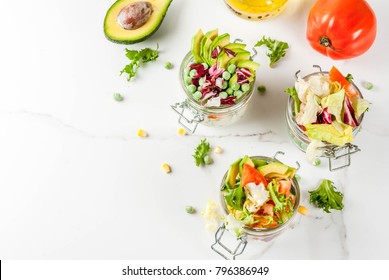 Fresh salads in jar with fresh vegetables and healthy dressings,  on white marble table, copy space