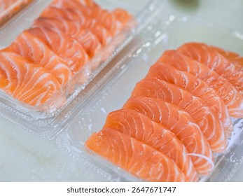 Fresh salmon sashimi neatly arranged in clear plastic trays, ready for takeaway or delivery, showcasing vibrant orange color and marbled texture.