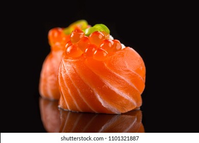 Fresh salmon sushi rolls with caviar isolated on black background.
