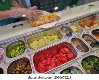 Fresh sandwich bar counter with person's hands cooks salad at sandwiches restaurant. for healthy and diet meal with smooth light and shadow.