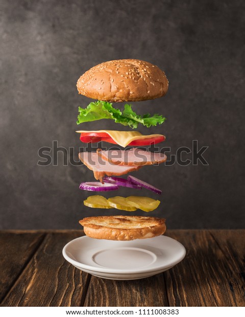 Fresh sandwich with flying ingredients\
isolated on wooden\
background