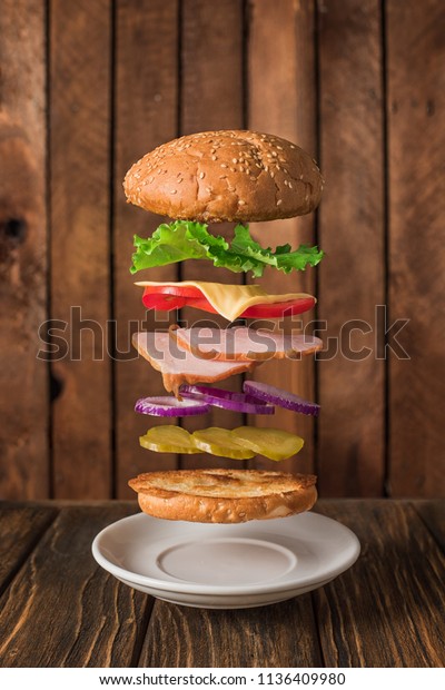 Fresh sandwich with flying ingredients\
isolated on wooden\
background