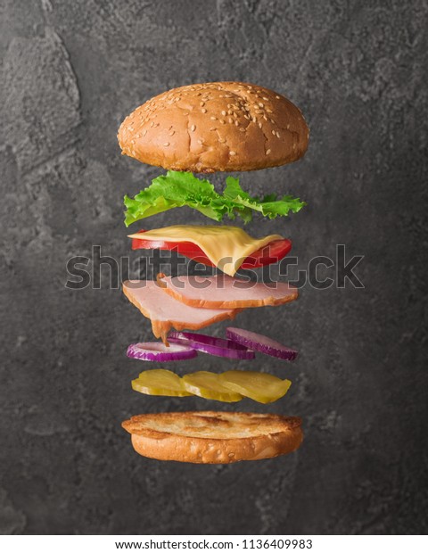 Fresh sandwich with flying ingredients\
isolated on concrete\
background