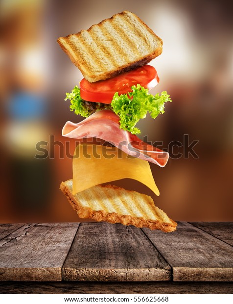 Fresh sandwich with\
flying ingredients placed on wooden planks. Copyspace for text,\
high resolution image