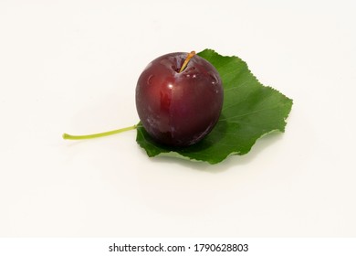 A Fresh Santa Rosa Plum And Leaf Isolated On A White Background..