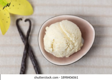Fresh scoop of vanilla ice cream with two vanilla pods and blossom from above